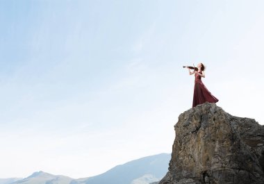 Keman ayakta rock üst kısmında oynayan genç çekici kız