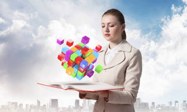 Kadın açık kitabın üzerinde uçan renkli 3D küplere bakıyor. Sanal gerçeklik soyut kare elementi olan yüksek teknoloji konsepti. Açık kitabı olan bir iş kadını. Şehir merkezindeki iş geçmişinde zarif bir bayan.