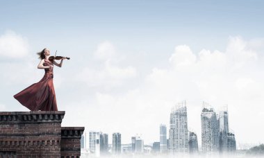 Genç çekici kız binasının tepesinde keman çalıyor. Karışık teknik