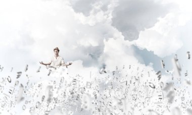 Beyaz elbiseli bir adam gözlerini kapalı tutuyor ve dikkatli bakıyor. Aynı zamanda havada uçan harflerin arasında meditasyon yapıyor. Arka planda bulutlu bir gökyüzü var..