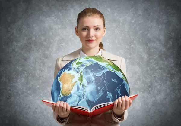 一个女人在书中展示了地球 全球生态概念 穿着白衣的优雅的年轻女子拿着一本关于灰色墙壁背景的书 环境友好型世界 — 图库照片