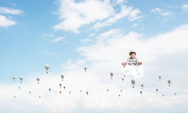 空を背景に曇った空を飛ぶ気球の間で瞑想しながら 目を閉じて集中して見ている若い男の子 — ストック写真