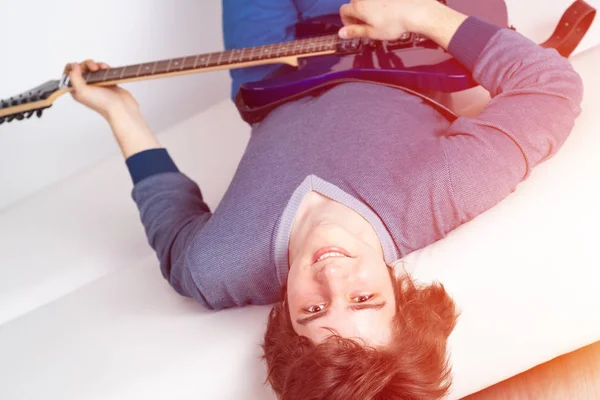 Glücklicher Junger Mann Der Mit Gitarre Auf Dem Sofa Liegt — Stockfoto