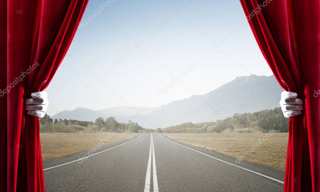 Asphalt road behind red curtain and hand holding it