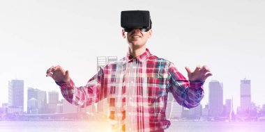 Sanal gerçeklik kulaklığı olan genç bir adam ya da şehrin arka planında 3 boyutlu gözlüklü.