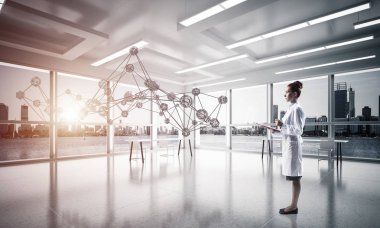 Beyaz hastane binası içinde ayakta iken sosyal ağ yapısını okuyan beyaz elbise emin kadın doktor yatay çekim. Medikal Sanayi konsepti