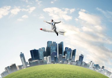 Cityscape ve mavi gökyüzü arka plan üzerinde ile roket üzerinde uçan takım elbiseli genç işadamı kavramsal görüntü.