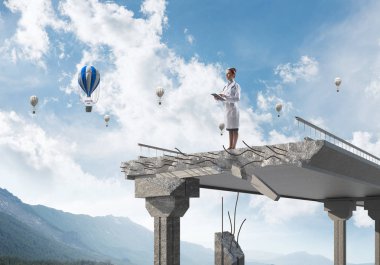 Peyzaj görünümü ve arka planda uçan hava balonları ile kırık köprünün kenarında ayakta iken tablet telefon kullanan profesyonel kadın doktor. Medikal Sanayi konsepti