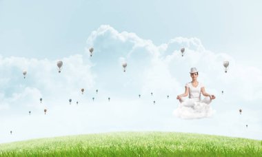 Genç kadın gözlerini kapalı tutuyor ve odaklanmış görünüyor. Arka planda parlak ve güzel manzarası olan uçan havacılar arasında bulutlar üzerinde meditasyon yapıyor..