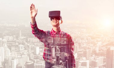 Sanal gerçeklik kulaklığı olan genç bir adam ya da şehrin arka planında 3 boyutlu gözlüklü.