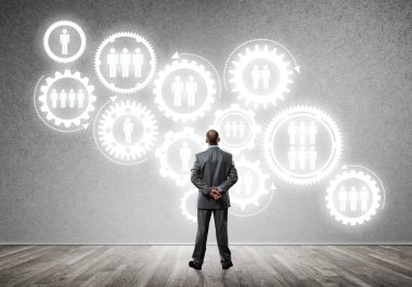 İş adamının çizilmiş dişli mekanizmasıyla duvara baktığı arka plan