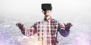 Sanal gerçeklik kulaklığı olan genç bir adam ya da şehrin arka planında 3 boyutlu gözlüklü.
