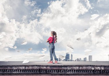 Sevimli kız etrafında uçan çatı ve kağıt uçaklar binasında ayakta