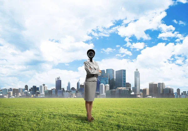 Камера очолила жінку, що стоїть на зеленій траві проти сучасного міського пейзажу — стокове фото