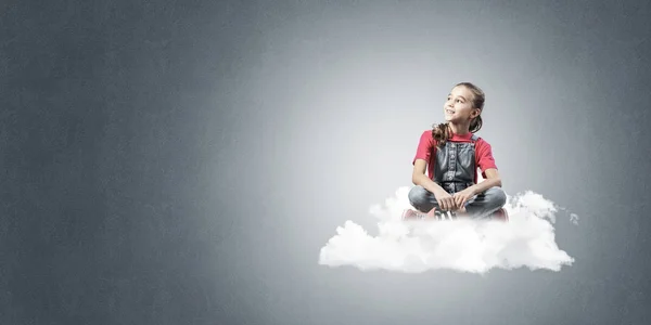 Niedliches Kind Mädchen Sitzt Auf Wolke Vor Blauem Hintergrund — Stockfoto