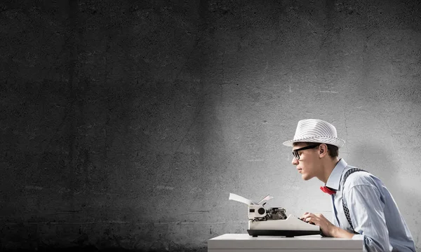 Joven Escritor Sombrero Anteojos Usando Máquina Escribir Mientras Está Sentado —  Fotos de Stock