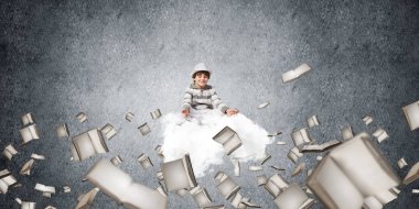 Genç küçük çocuk gözleri koruma kapalı ve seyir üzerinde uçan bulut kitaplar ile gri karanlık duvar arka plan üzerinde uçan arasında meditasyon sırasında konsantre.