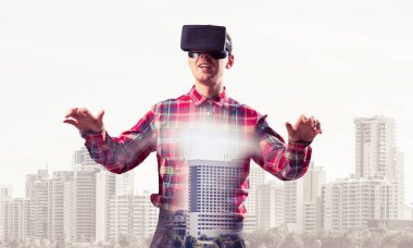 Sanal gerçeklik kulaklığı olan genç bir adam ya da şehrin arka planında 3 boyutlu gözlüklü.