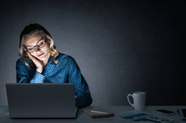 Genç bir kadın gece geç saatlerde odasında ya da ofisinde oturuyor. Karışık ortam