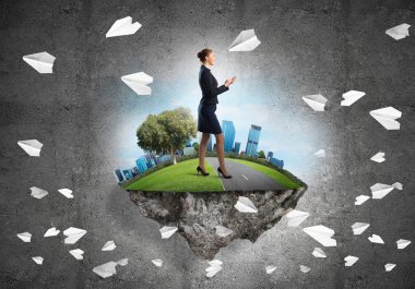 Yeşil yüzen adada beton zemine karşı duran kendine güvenen zarif bir iş kadını.