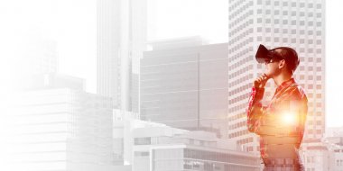 Sanal gerçeklik kulaklığı olan genç bir adam ya da şehrin arka planında 3 boyutlu gözlüklü.