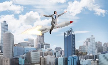 Arka plan üzerinde modern cityscape gökdelenler ve mavi gökyüzü ile roket üzerinde uçan takım elbiseli Genç ve mutlu işadamı kavramsal görüntü.