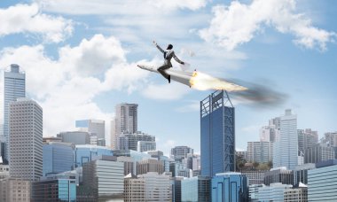 Arka plan üzerinde modern cityscape gökdelenler ve mavi gökyüzü ile roket üzerinde uçan takım elbiseli genç işadamı kavramsal görüntü.