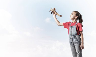 Elinde retro uçak modeliyle tulumlu şirin bir kız çocuğu.