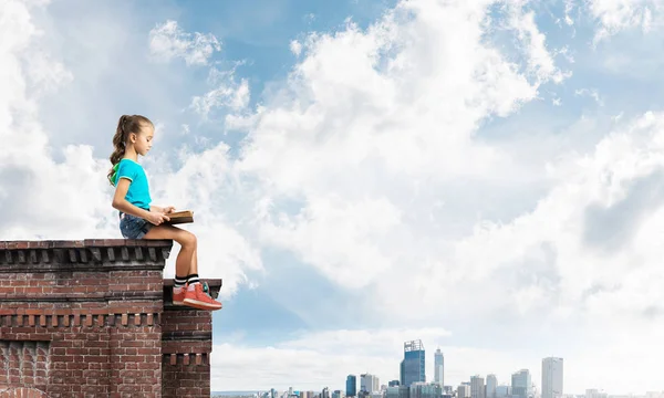 建物の屋根や本を読んで座っているかわいい子供女の子 — ストック写真