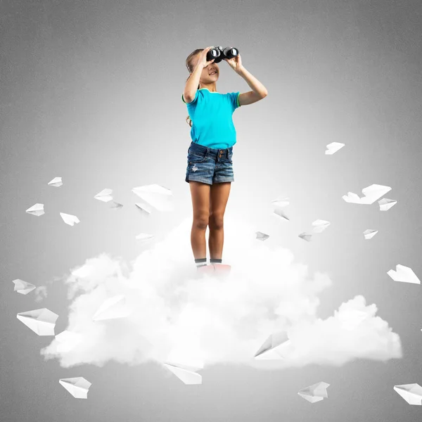 双眼鏡で紙飛行機を飛んでいる雲に立っているかわいい子供女の子 — ストック写真