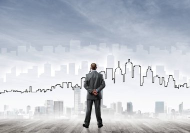 İşadamı arkasını dönüp modern iş merkezinin siluetine bakıyor.