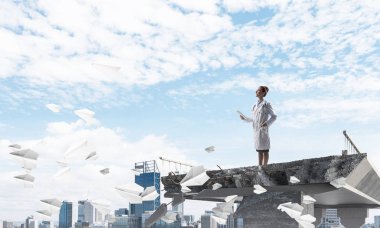 Arka planda Cityscape görünümü ile kırık köprünün kenarında uçan kağıt uçakları arasında ayakta iken tablet kullanan profesyonel kadın doktor. Medikal Sanayi konsepti