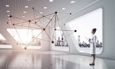 Beyaz hastane binası içinde duran ve siyah ağ yapısını inceleyerek, güvenli tıbbi sanayi çalışanı yatay çekim. Tıbbi sanayi için modern teknolojiler. Genç kadın doktor