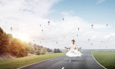 Genç adam gözleri koruma kapalı ve seyir ile güzel ve nefes kesici manzara arka plan üzerinde bulut yukarıda yolun üzerinde meditasyon sırasında konsantre.