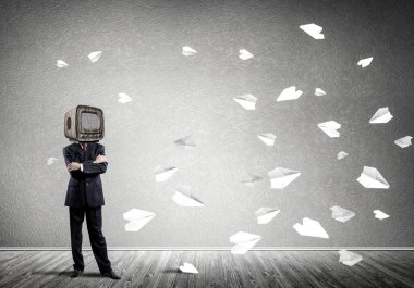 Kağıt uçaklar ile gri karanlık duvar boş oda içinde arka planda uçan arasında dururken kafasına silah tutmak yerine eski Tv ile takım elbiseli işadamı geçti.