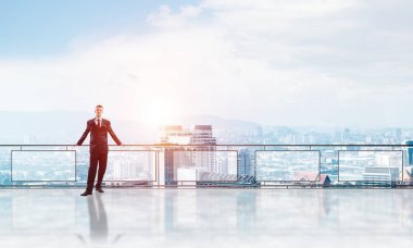 Gökdelenlerin üzerinde gün doğumu ve yeni bir güne bakan iş adamı