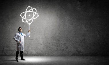 Arka plan gri beton duvara karşı dururken moleküler yapısı ile beyaz üniforma interracting başarılı ve genç doktor kavramsal görüntü.