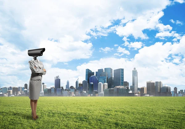 Kamera głowica kobieta stojąc na zielonej trawie przeciw nowoczesny miejski krajobraz — Zdjęcie stockowe