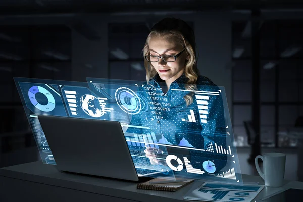 Çekici bir kadın gece ofisinde oturmuş dizüstü bilgisayarına bakıyor. Karışık ortam