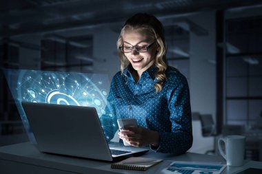 Dizüstü bilgisayarda çalışan çekici bir kadın ve ikonu ekrandan uzak tutuyor. Karışık ortam