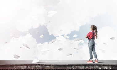 Sevimli kız etrafında uçan çatı ve kağıt uçaklar binasında ayakta