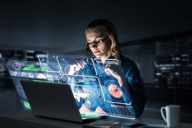 Çekici bir kadın gece ofisinde oturmuş dizüstü bilgisayarına bakıyor. Karışık ortam