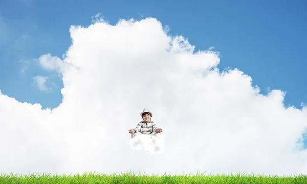 雲の上で瞑想しながら目を閉じて集中して見ている若い男の子背景に明るく美しい風景と — ストック写真