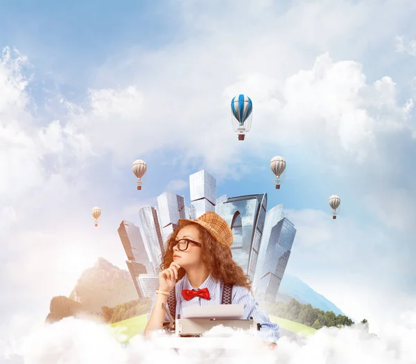 年轻而美丽的女作家在帽子和眼镜使用打字机 而坐在桌子上与浮动城市岛屿和多云的天空景与飞行的空气定子背景 — 图库照片