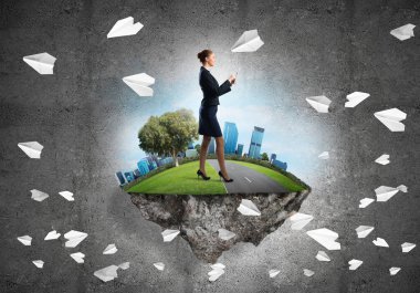 Yeşil yüzen adada beton zemine karşı duran kendine güvenen zarif bir iş kadını.