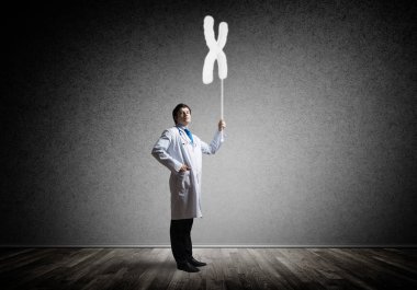 Arka plan gri duvara karşı dururken parlayan Dna simgesi olan beyaz tıbbi üniforma interracting genç emin doktor yatay çekim.