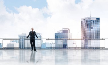 Gökdelenlerin üzerinde gün doğumu ve yeni bir güne bakan iş adamı