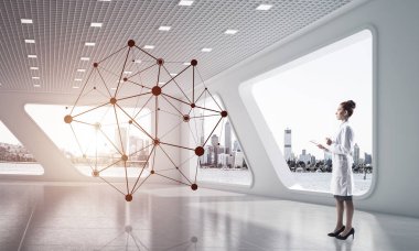 Beyaz takım elbiseli genç ve profesyonel kadın doktor beyaz hastane binasında dururken ağ yapısını inceliyor. Tıp endüstrisi konsepti