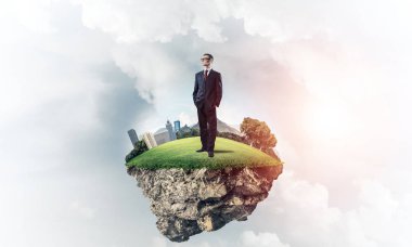 Mavi gök yeşil yüzen ada üzerinde duran zarif emin iş adamı