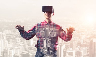 Sanal gerçeklik kulaklığı olan genç bir adam ya da şehrin arka planında 3 boyutlu gözlüklü.